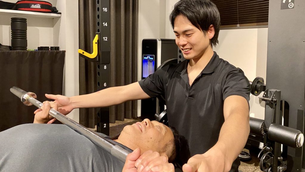 パーソナルトレーニングでベンチプレスを習う男性
